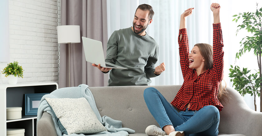 excited couple looking at laptop